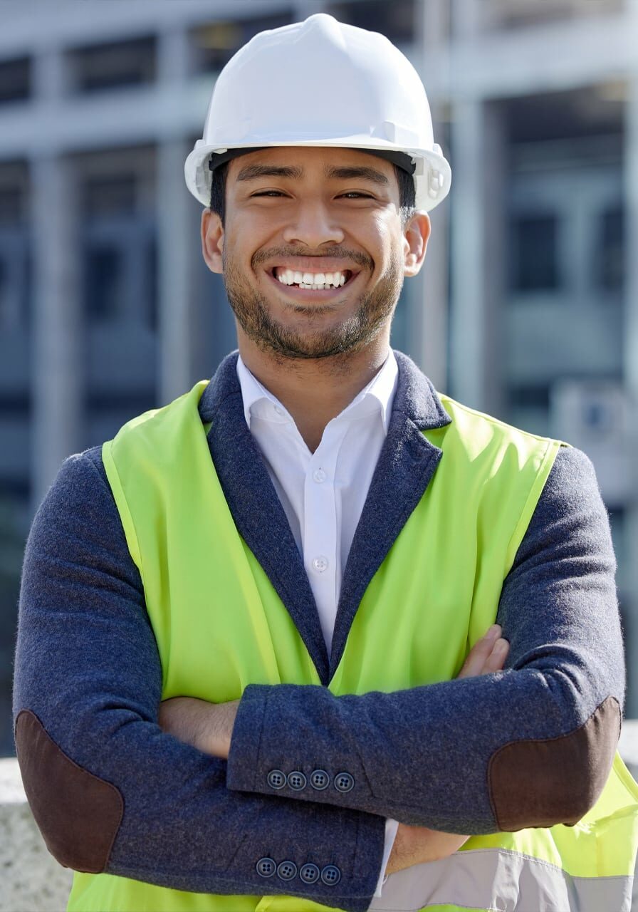 Young engineer standing on top of a building with a yellow vest and a hard hat
